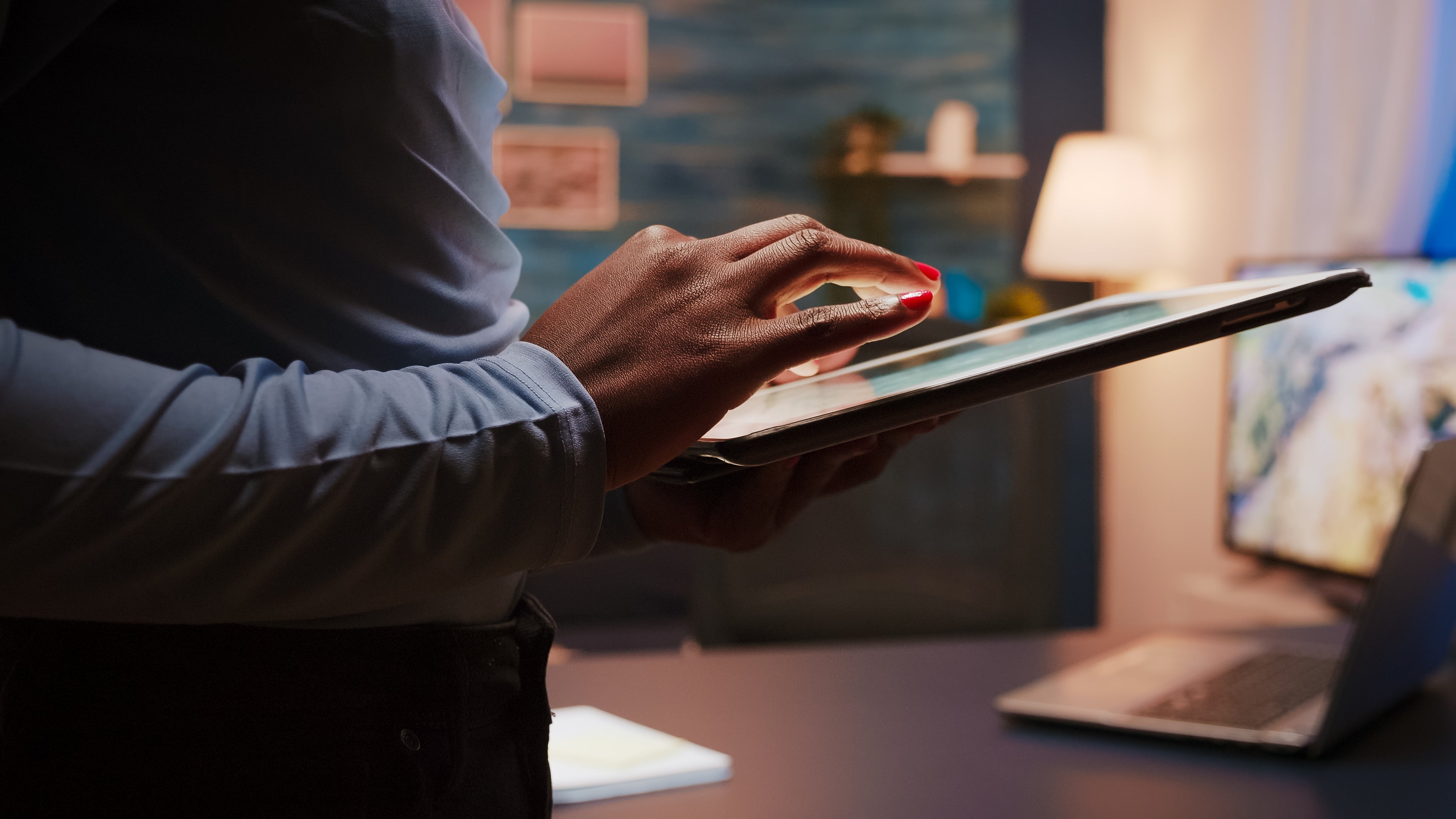Close-up of a woman holding a tablet in a modern workspace, symbolizing digital work and connectivity.